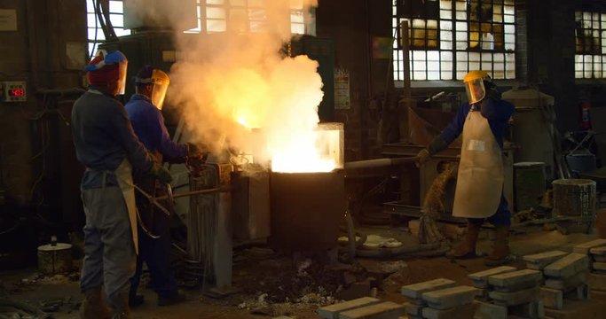 Worker melting metal in foundry workshop 