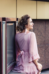 Fototapeta premium attractive young girl in a short pink dress posing near a beautiful building.