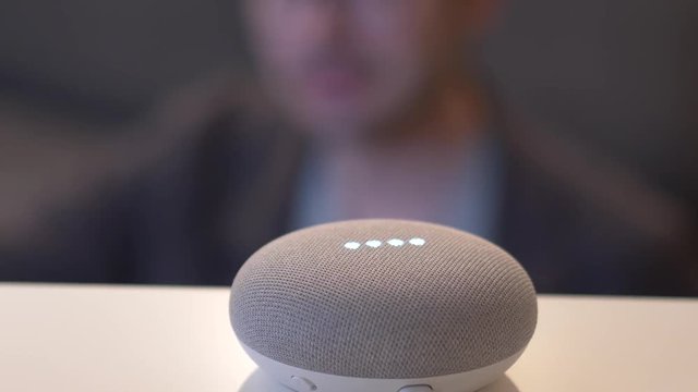 A person in the background activating his smart home assistant by voice.