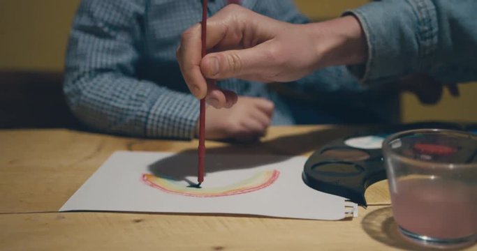 Little toddler painting water colors with his mother