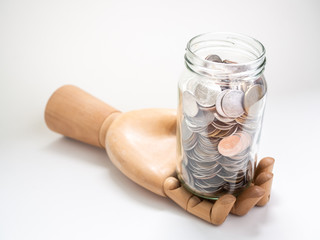 Coins in glass jar on wooden hand isolated on white background