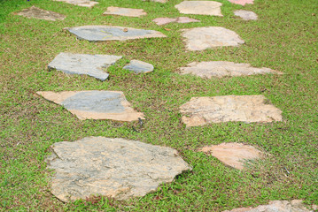 Stone pathway in the park with green grass around.