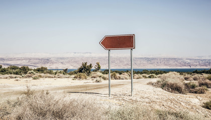 Road sign arrow in rural area near water moody