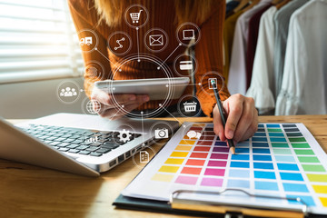 Fashion designer woman talking smart phone and using laptop with digital tablet computer in modern studio in morning light