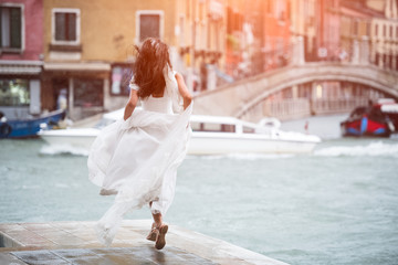 Back View of young bride running to lake. Italy, Venice.