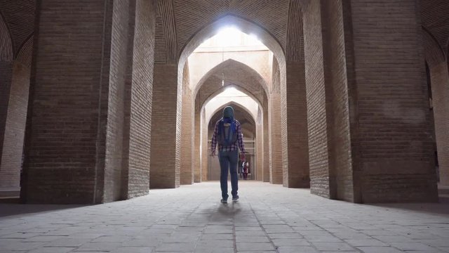 Female tourist walking along vaulted arch passageway, Isfahan