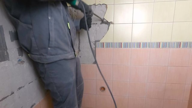 Demolition of old tiles with jackhammer. Renovation of old walls in the bathroom or kitchen