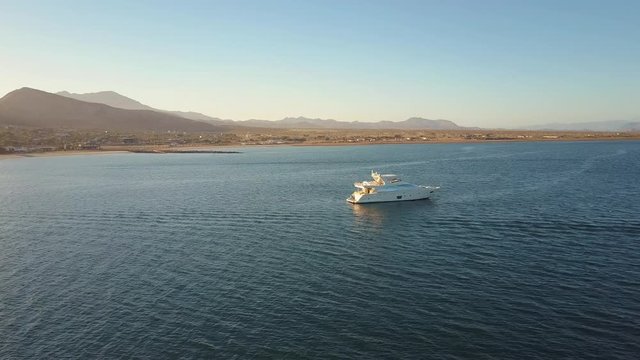 Aerial, gorgeous sunset over Bahia de los Angeles, Baja California, Mexico, flying past yacht towards beach.
