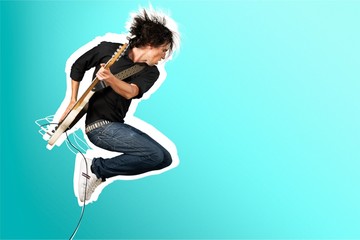 Male Guitarist playing music on grey wall background