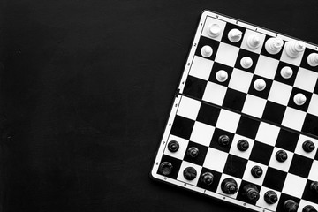 Chess game concept. Chess board with figures on black background top view copy space