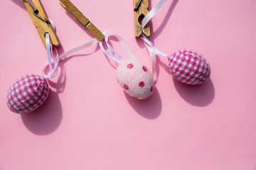 colorful Easter Eggs with Cross hanging on line from clothespins.Still Life Easter eggs hanging on a rope on pink background. Easter holiday concept.Copy space