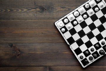 Chess game concept. Chess board with figures on dark wooden background top view copy space