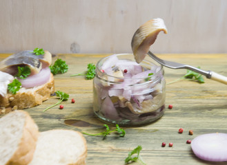 sandwich with herring and onions, fork on wooden background selective focus