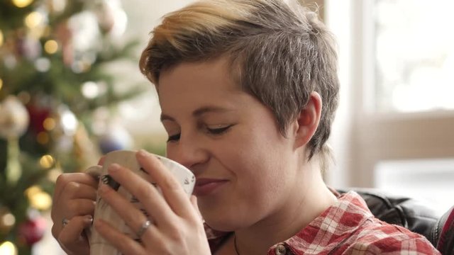 Edgy young woman drinks tea and smiles.