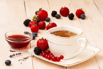 Herbal tea with lavender and mint, homemade jam, fresh strawberries, blackberries and blueberries on a white wooden table. Berry tea with fresh strawberry, blackberry.