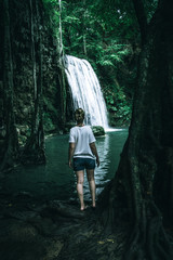 A wild natural fresh sparkling waterfall in a lonely green valley with moos covered rocks and ice cold mountain water flowing down black rocky walls on a rainy moody day in Iceland without tourists