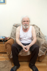 Old sick lonely man in the armchair at home