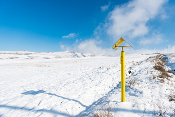 Naklejka na ściany i meble Winter landscape, yellow pillar, gas pointer on the slope of a snowy mountain