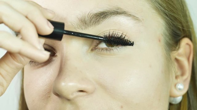 Close-up girl's eyes apply carcass on eyelashes, make-up in a professional beauty salon