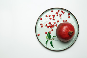 Plate with ripe pomegranate on white background