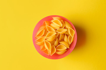 Uncooked conchiglie pasta on color background