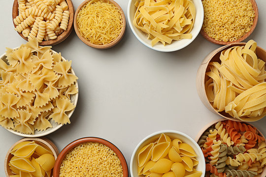 Frame made of assortment pasta on grey background