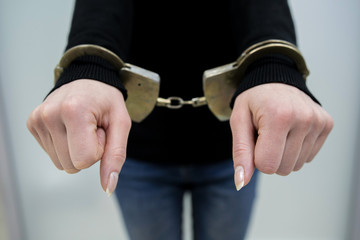 Close-up. Arrested man handcuffed hands at the back isolated on gray background. Prisoner or arrested terrorist, close-up of hands in handcuffs.