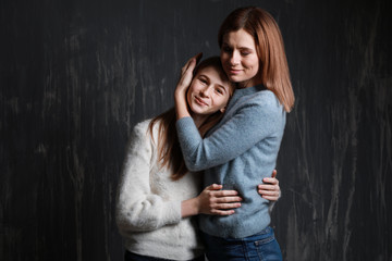 Portrait of happy mother and daughter on dark background