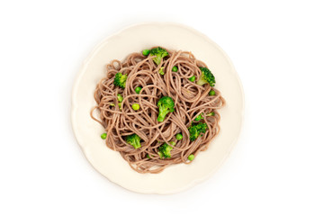 A plate of soba, buckwheat noodles with green vegetables, shot from the top on a white background with copy space