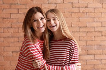 Portrait of happy mother and daughter on brick background