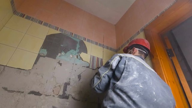 Demolition of old tiles with jackhammer. Renovation of old walls in the bathroom or kitchen