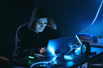 Professional hacker using laptop in dark room