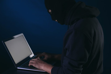 Professional hacker with laptop on dark background