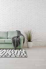 Comfortable sofa near white brick wall in interior of room
