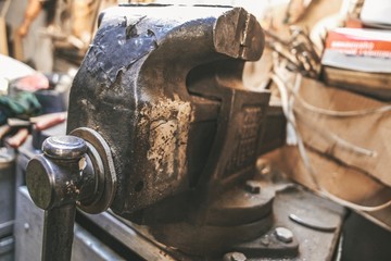 Dirty gloomy messy garage, where parts, construction tools lying around. Different parts of the equipment, vehicles.