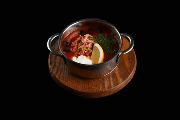 Traditional Russian soup Solyanka cooked with meat, sausages, salted cucumbers and olives.