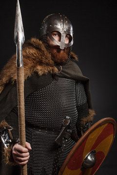 Warrior Viking in full arms with axe, shield and spear on dark background