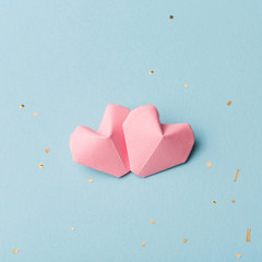 two pink hearts and Golden tinsel on a light blue background. Valentines day or wedding