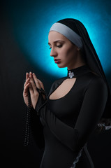 Fine art portrait of a novice nun in deep prayer with rosary - obrazy, fototapety, plakaty