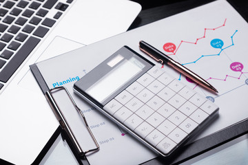 Modern calculator is on a laptop and on a sheet with a graph