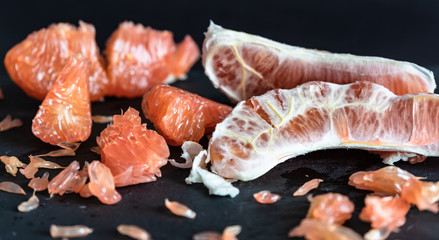 Pomelo mit rotem Fruchtfleisch vor dunklem Hintergrund