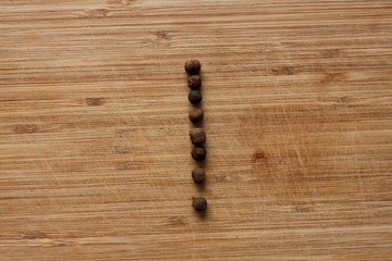 Capital characters made of peppercorns. Alphabet letters on wood background.