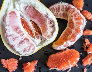 Pomelo mit rotem Fruchtfleisch vor dunklem Hintergrund