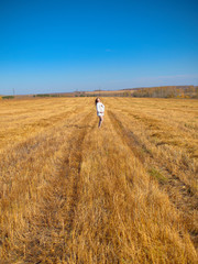 Beautiful pregnant woman in a white woolen sweater. Happy pregnant woman posing on a mown wheat field.