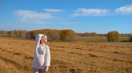 Naklejka na ściany i meble Beautiful pregnant woman in a white woolen sweater. Happy pregnant woman posing on a mown wheat field.