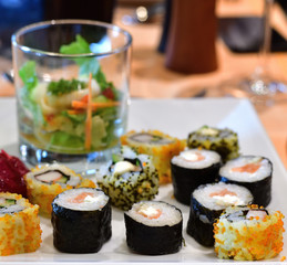 Set of sushi and salad in a glass on white plate