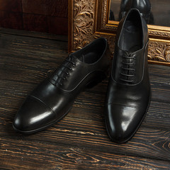 Black oxford shoes with golden picture frame on dark background