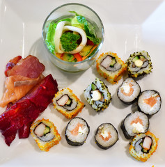 Set of sushi and salad in a glass on white plate