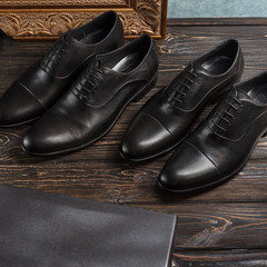 Two pairs of black oxford men shoes with golden picture frame