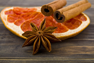 dried grapefruit, cinnamon sticks and anise stars on wooden background